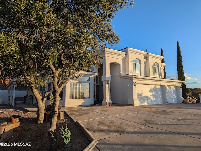 view of front of house with an attached garage, driveway, and stucco siding