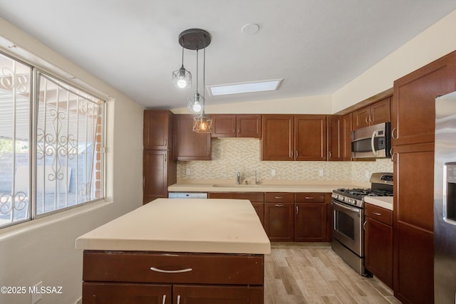 kitchen featuring pendant lighting, stainless steel appliances, tasteful backsplash, light countertops, and a sink