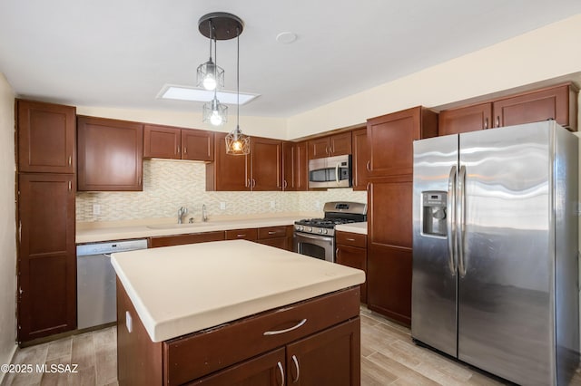 kitchen with a sink, light wood-style floors, appliances with stainless steel finishes, decorative backsplash, and pendant lighting