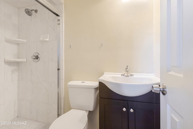 bathroom featuring a tile shower, vanity, and toilet