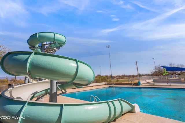 community pool featuring a water slide and fence