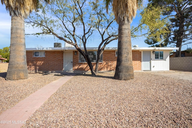 ranch-style house featuring brick siding and fence