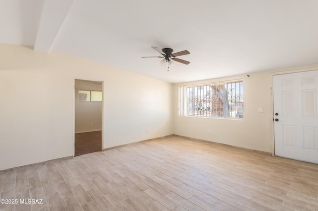 empty room with ceiling fan, light wood-type flooring, and lofted ceiling