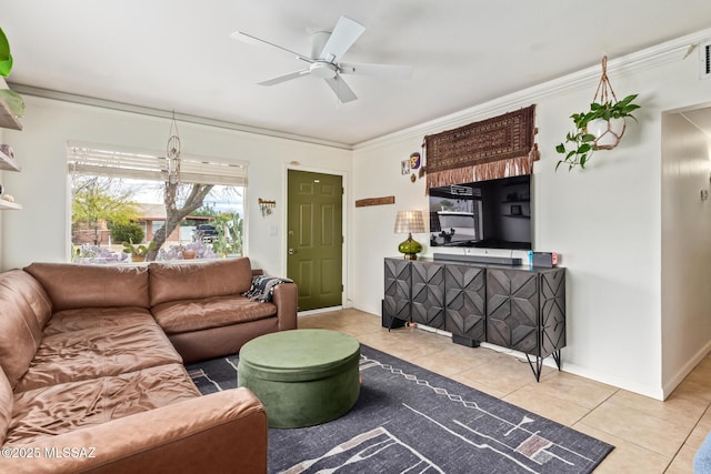 living room featuring baseboards, light tile patterned flooring, a ceiling fan, and ornamental molding