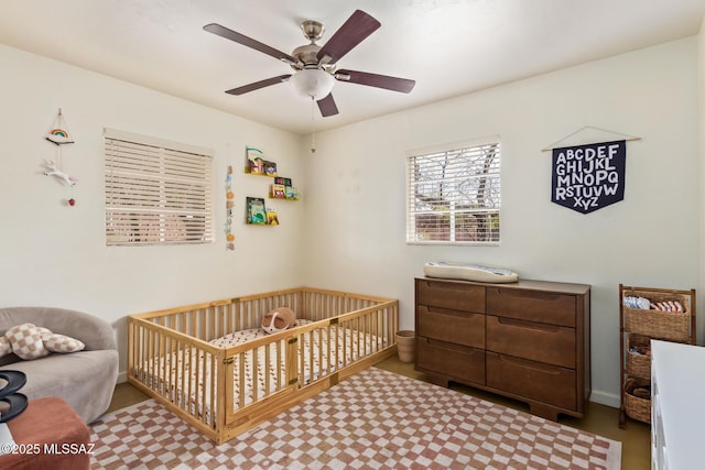 bedroom with a nursery area, ceiling fan, and carpet