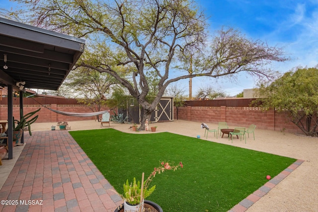 view of yard featuring a fenced backyard, a patio, an outbuilding, and a storage shed