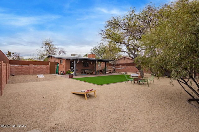 exterior space featuring a patio, a yard, a fenced backyard, and a chimney