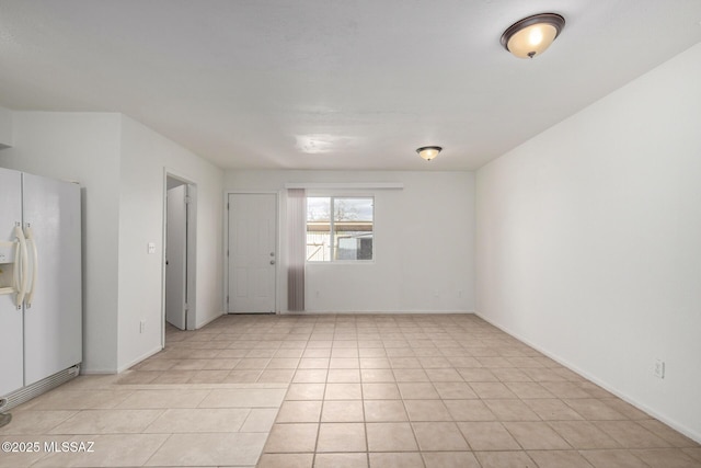 spare room featuring light tile patterned floors and baseboards