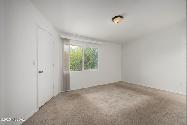 carpeted empty room featuring baseboards