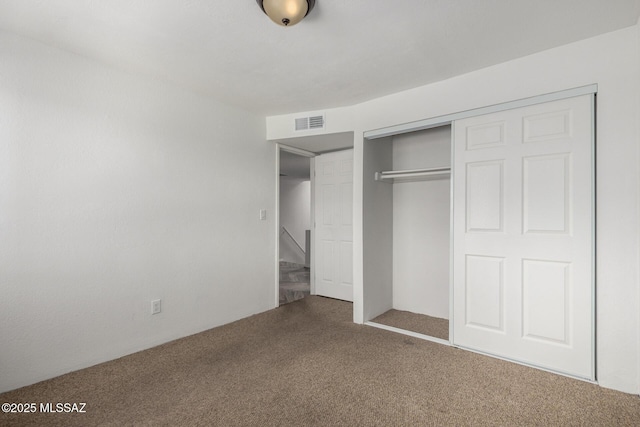 unfurnished bedroom with carpet floors, a closet, and visible vents