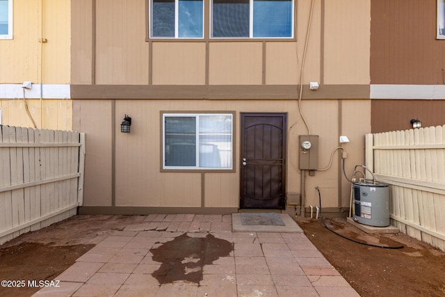 doorway to property with a patio area, water heater, and fence