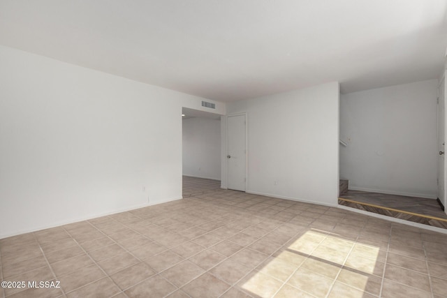 spare room featuring light tile patterned floors, visible vents, and baseboards