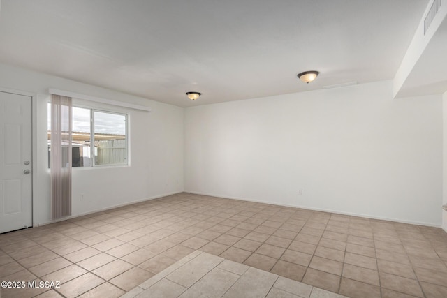 empty room with baseboards, visible vents, and light tile patterned flooring