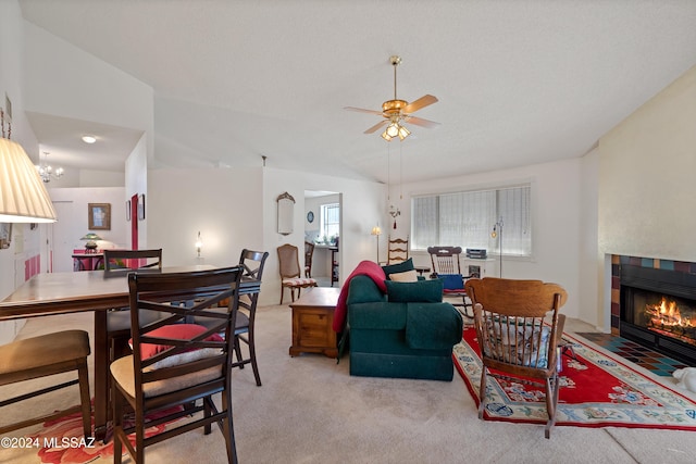 living area with lofted ceiling, a fireplace, a ceiling fan, and light colored carpet