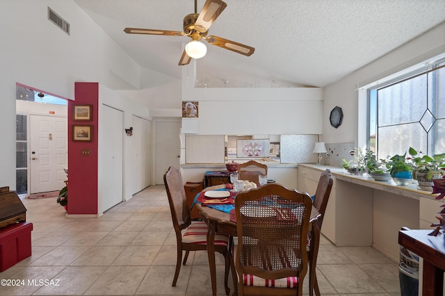 dining space with lofted ceiling, ceiling fan, a textured ceiling, light tile patterned flooring, and visible vents