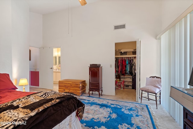 carpeted bedroom with a walk in closet, a closet, visible vents, and a towering ceiling