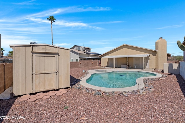 view of swimming pool with an outbuilding, a fenced backyard, a fenced in pool, a storage unit, and a patio area