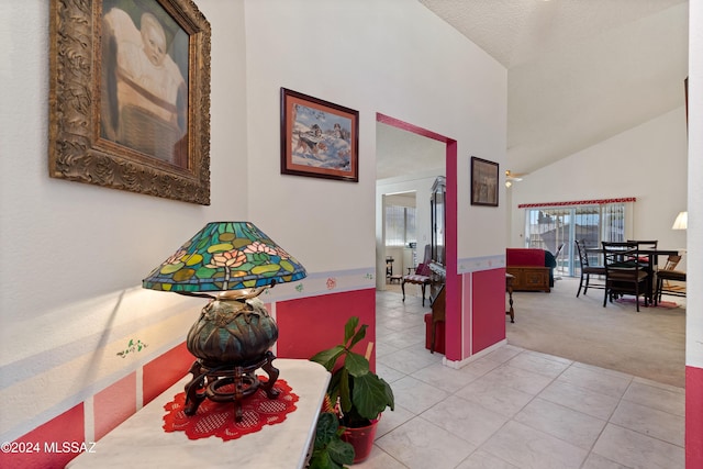 interior space with light tile patterned flooring, high vaulted ceiling, and light colored carpet