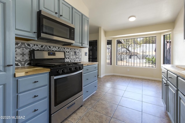 kitchen featuring tasteful backsplash, appliances with stainless steel finishes, wooden counters, and light tile patterned flooring