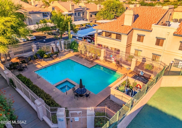 community pool featuring a patio, fence, and a hot tub