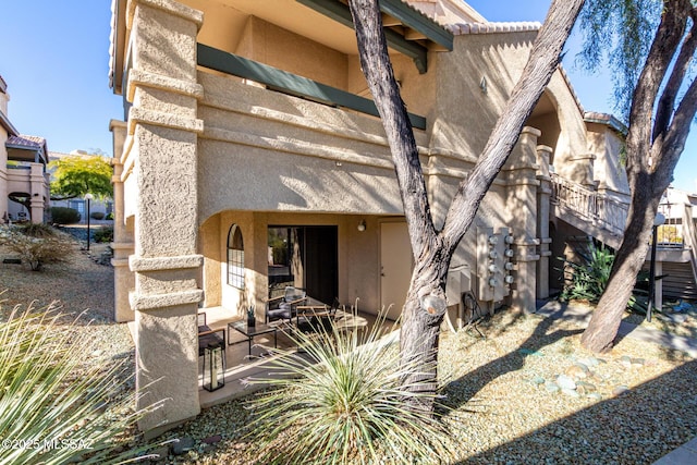 rear view of property with a tile roof and stucco siding