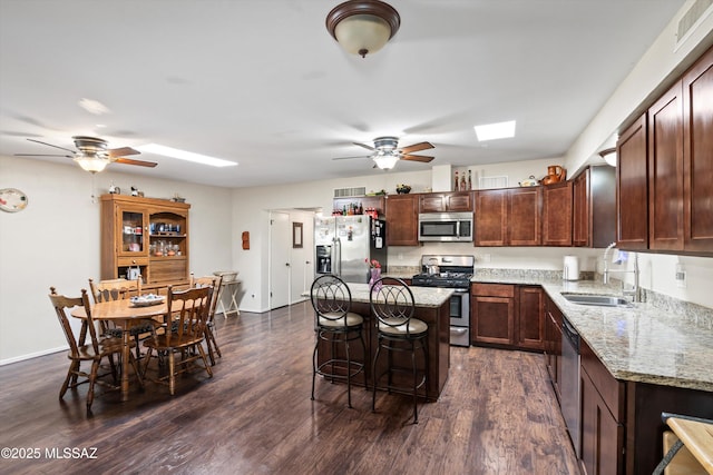 kitchen featuring visible vents, ceiling fan, a breakfast bar area, stainless steel appliances, and a sink