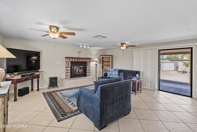 living room featuring light tile patterned floors, a ceiling fan, visible vents, baseboards, and a brick fireplace