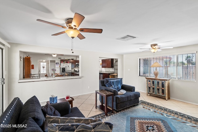 living room featuring tile patterned floors, a ceiling fan, visible vents, and baseboards