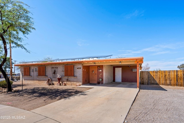 view of front of home with an attached carport, concrete driveway, and fence