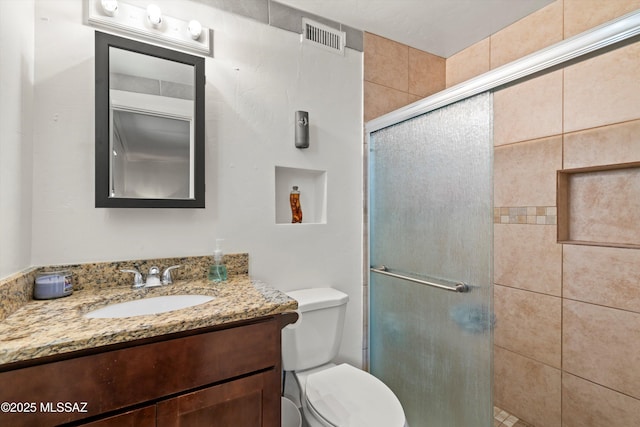 bathroom with visible vents, toilet, a stall shower, and vanity