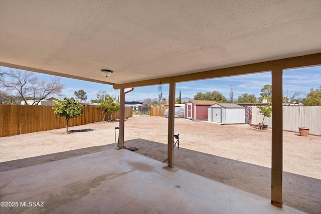 view of patio with an outdoor structure, a storage unit, and a fenced backyard