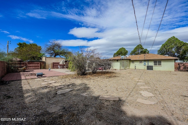 view of yard with cooling unit, fence, and a patio