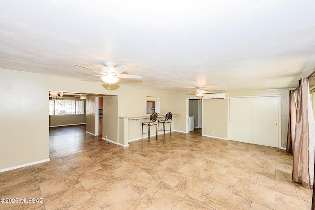 unfurnished room featuring ceiling fan, an AC wall unit, and baseboards