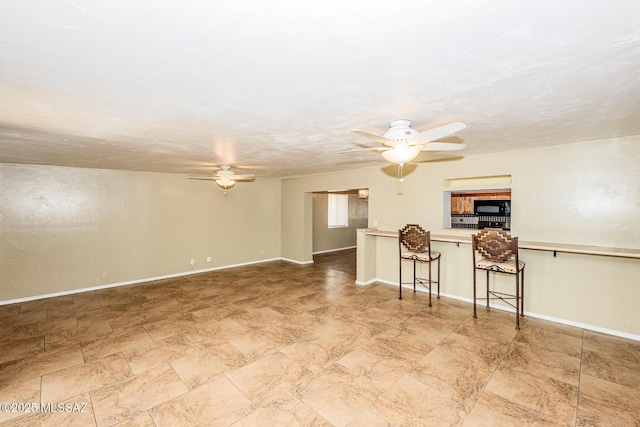 unfurnished living room featuring a textured ceiling, baseboards, and a ceiling fan