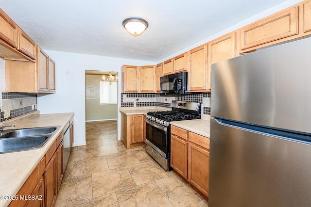 kitchen featuring tasteful backsplash, light countertops, appliances with stainless steel finishes, a sink, and baseboards