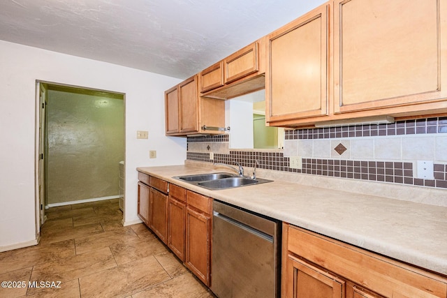 kitchen featuring baseboards, decorative backsplash, light countertops, stainless steel dishwasher, and a sink