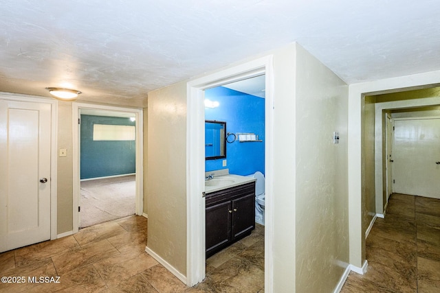 hall with baseboards and a sink