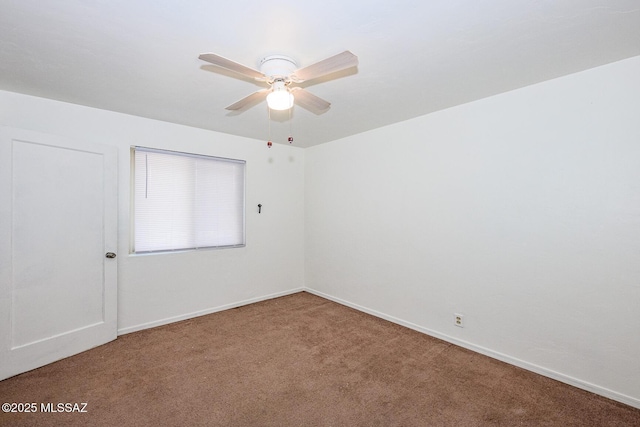 carpeted spare room featuring baseboards and a ceiling fan