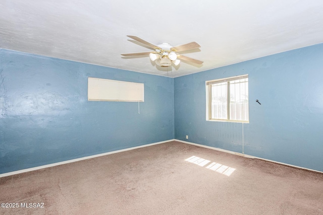 carpeted empty room featuring baseboards and a ceiling fan