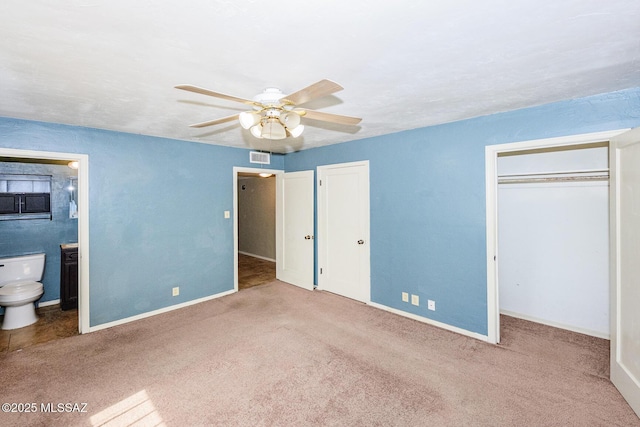 unfurnished bedroom with ensuite bathroom, visible vents, baseboards, multiple closets, and carpet