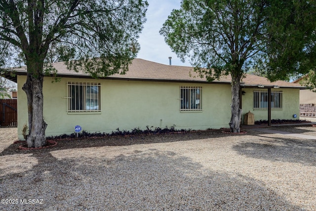 view of front of home featuring roof with shingles, fence, and stucco siding