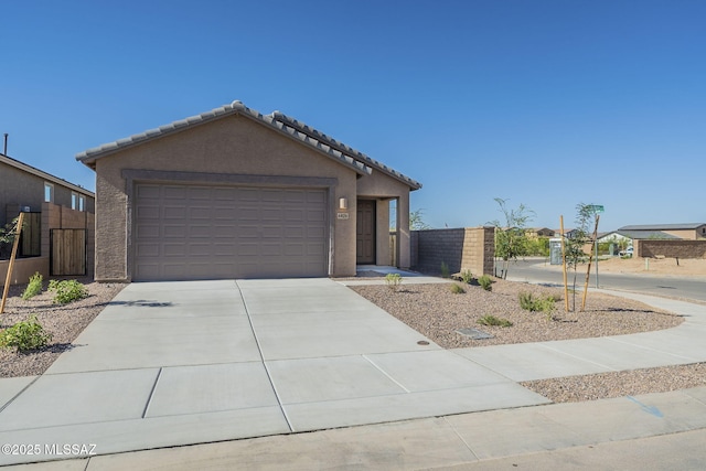 view of front facade featuring a garage, driveway, a tiled roof, fence, and stucco siding