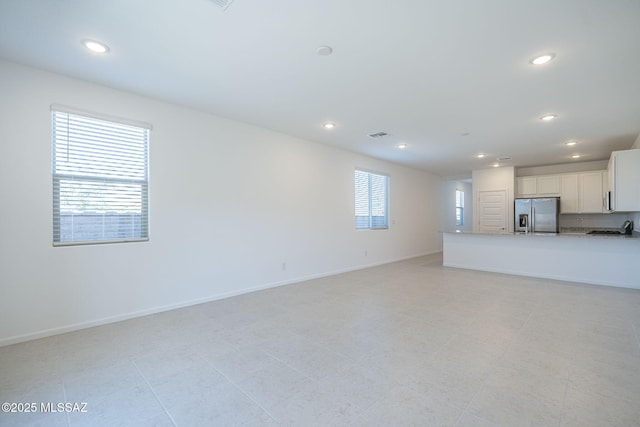 unfurnished living room with recessed lighting and baseboards