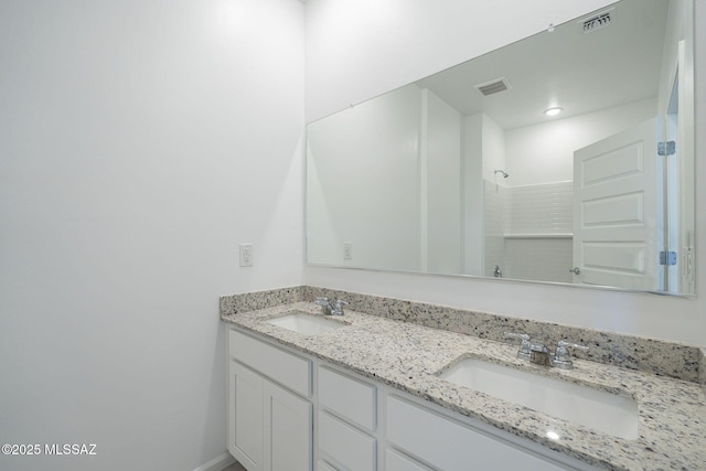 full bath featuring double vanity, walk in shower, a sink, and visible vents