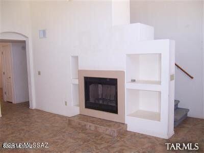 unfurnished living room featuring stairway and a glass covered fireplace