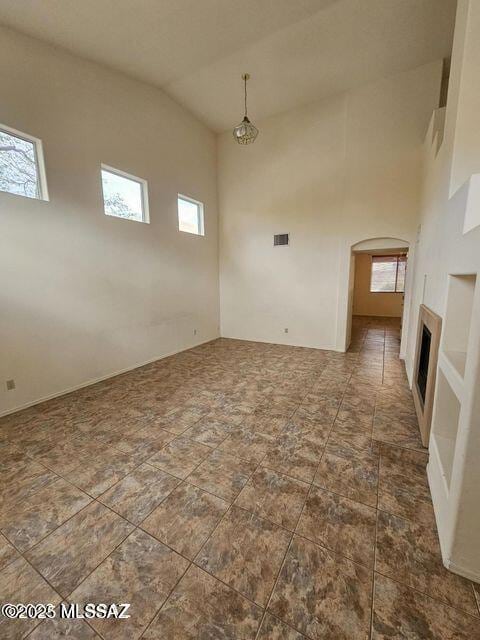 interior space featuring arched walkways, a fireplace, visible vents, and a healthy amount of sunlight