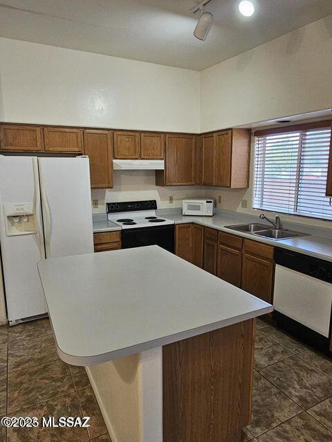 kitchen featuring white appliances, a kitchen island, light countertops, under cabinet range hood, and a sink