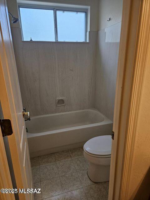 bathroom featuring toilet, tile patterned flooring, a wealth of natural light, and shower / bathtub combination