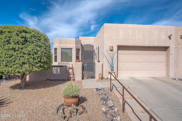 pueblo-style home featuring driveway, a garage, a fenced front yard, a gate, and stucco siding