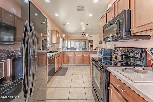 kitchen with a peninsula, black appliances, light tile patterned floors, and light countertops